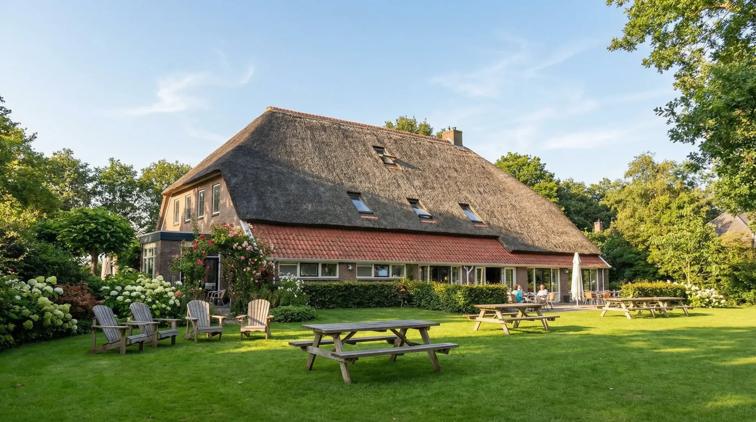 De rietgedekte boerderij met gazon en picknicktafels