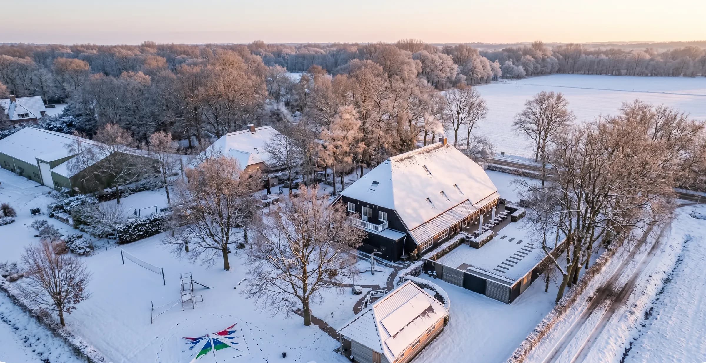 Luchtfoto van Orvelter Hof in de sneeuw, met de boerderij, de tuin en de besneeuwde velden eromheen