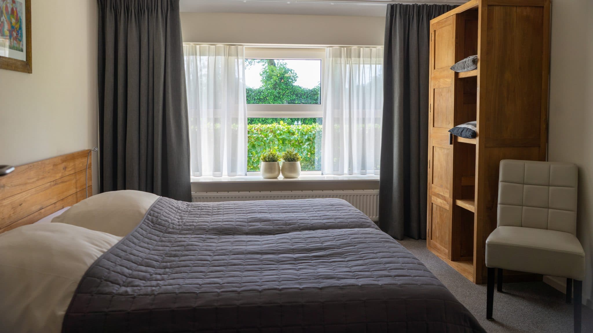 Slaapkamer met boxspring en uitzicht op de tuin bij Orvelter Hof