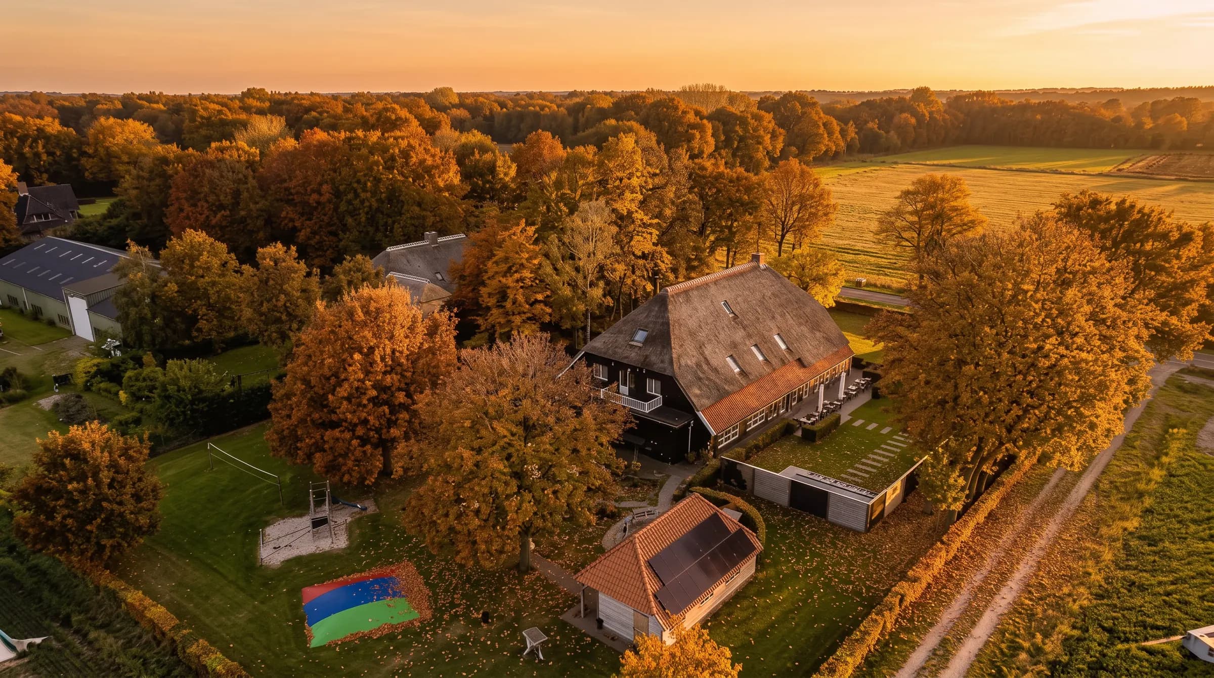 Luchtfoto van Orvelter Hof in de herfst bij zonsondergang, tussen goudkleurige bomen en weilanden